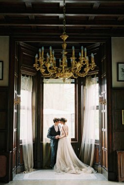 Groom hugs bride standing on the balcony of an old villa. Como, Italy. High quality photo
