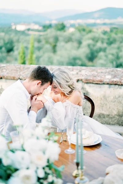 Groom Kisses Bride Hands While Sitting Table Terrace High Quality — Φωτογραφία Αρχείου