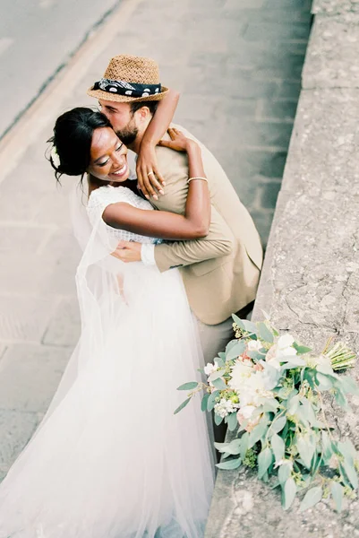 Groom hugs and kisses bride near the stone fence. Top view. High quality photo