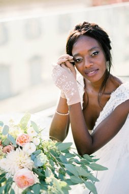 Bride in gloves sits propping her head with her hands at the table. High quality photo
