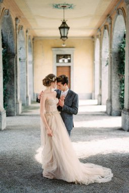 Bride and groom stand hugging on the terrace of an old villa. High quality photo