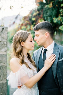 Bride and groom stand in an embrace against a stone wall. Portrait. High quality photo