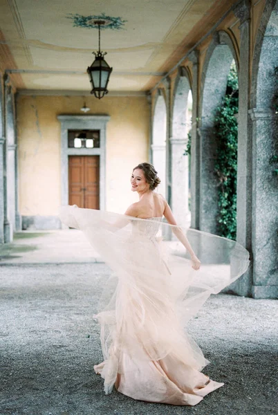 Bride in a beige dress is spinning around the terrace of an old villa. Como, Italy. High quality photo