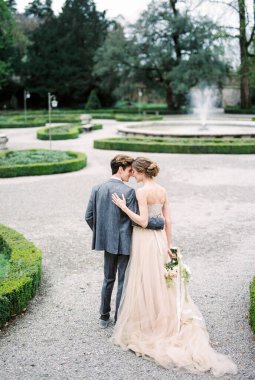 Bride and groom stand embracing in the park. Back view. High quality photo