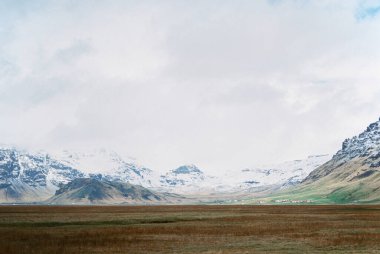 Valley with dry grass against the backdrop of snow-capped mountains. Iceland. High quality photo