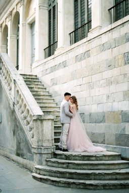 Bride and groom are standing on the stone steps of an old building. Bergamo, Italy. High quality photo