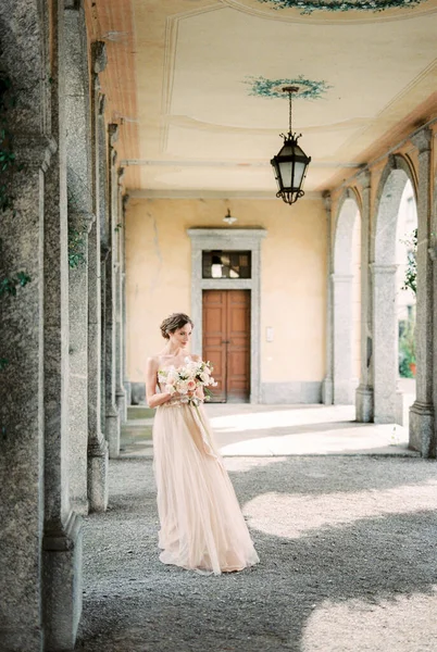 Bride with a bouquet of flowers in her hands on the terrace of an old villa. Como, Italy. High quality photo