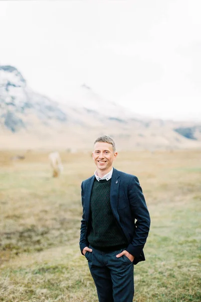 Smiling man in a suit stands in a pasture. Iceland. High quality photo