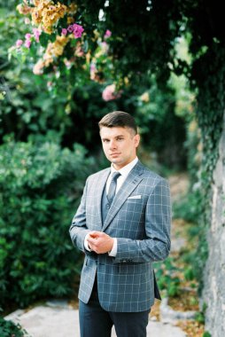 Man in a gray checkered suit stands under a flowering tree. High quality photo