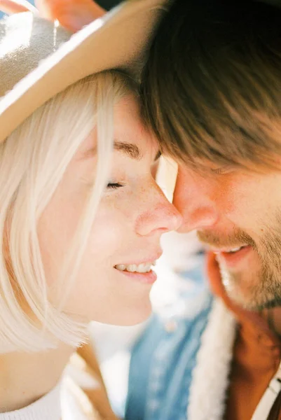 Woman in a hat touches a man nose with her nose. Portrait. High quality photo