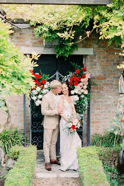 Groom Hugs Bride Old Building Decorated Flowers High Quality Photo — Photo