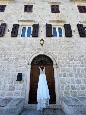 Gelinlik pencerelerinde panjurlar olan eski bir taş evin kapısında asılı. Yüksek kalite fotoğraf