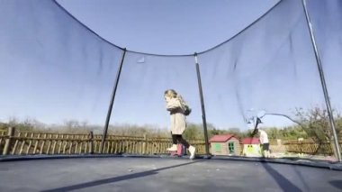 Little girl runs on a trampoline arena on the playground. High quality 4k footage