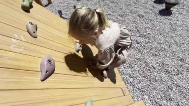 Little girl climbs the climbing wall at the playground. High quality 4k footage