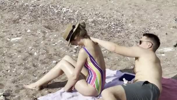 Man Rubbing Suntan Lotion Woman Back Pebble Beach High Quality — Stok video