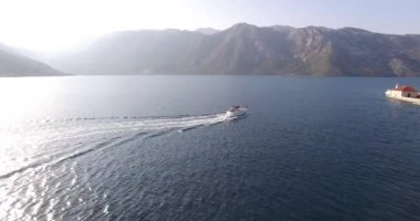 White yacht sails on the sea past the island of Gospa od Skrpjela. High quality 4k footage
