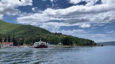 The ferry floats near the shore against the backdrop of a green mountain in the bay. High quality 4k footage