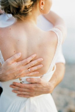 Groom arms hug bride back. Close-up. High quality photo