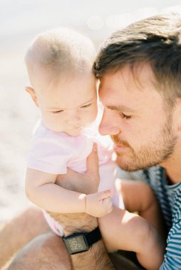 Dad hugging a baby sitting on his lap. High quality photo