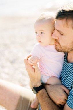 Dad hugs a baby sitting in his arms. High quality photo