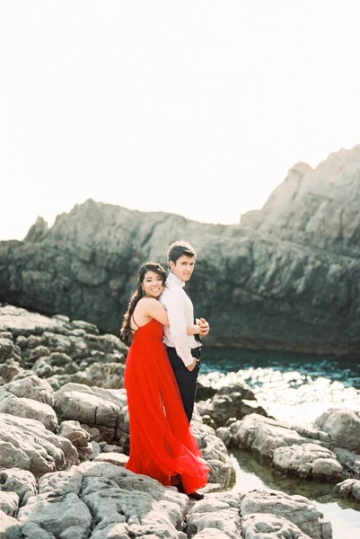 Woman Red Dress Hugs Man Standing Rocks High Quality Photo — Stock fotografie