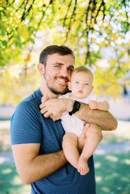 Smiling dad holds a baby in his arms, hugging him. Portrait. High quality photo