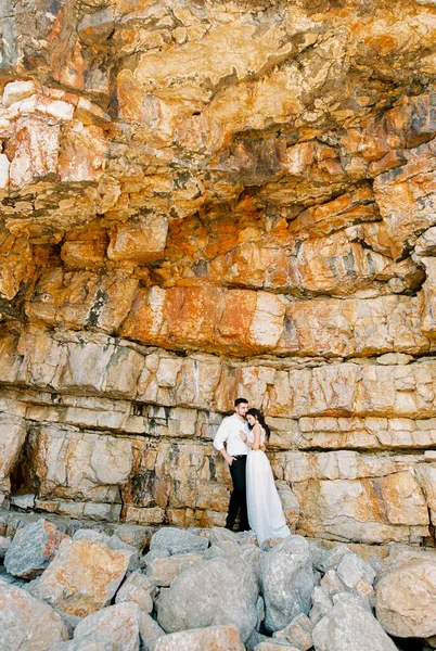Bride and groom stand embracing on a sheer cliff. High quality photo