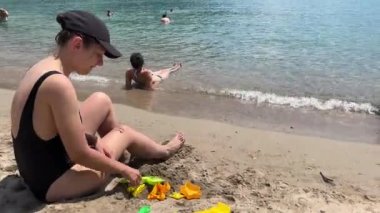 Young woman on the beach spending time with her little daughter. High quality 4k footage