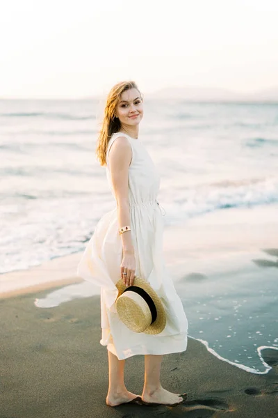 Smiling Woman Dress Straw Hat Her Hand Stands Sand Sea — Stok Foto