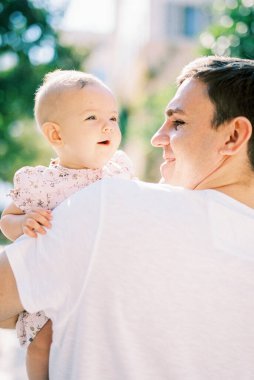 Smiling dad holds a little baby girl in his arms. Back view. High quality photo