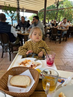 Little girl sitting at a table in a cafe after dinner. High quality photo