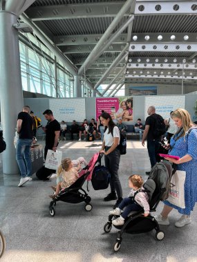 Mothers with children in strollers stand in line at the airport lounge. High quality photo