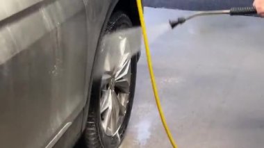 Car washer washing car wheels with foam at car wash. High quality FullHD footage