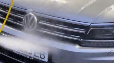 Car washer washing the car with foam from a hose. High quality FullHD footage