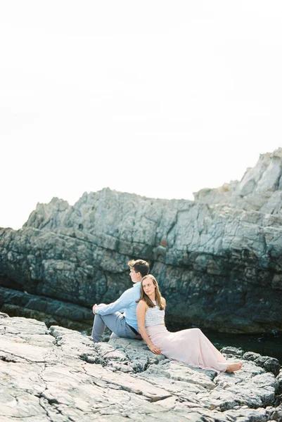 Man and woman sit back to back on a rock. High quality photo