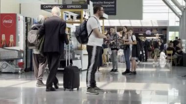 Man with a suitcase on wheels walks through the airport terminal maneuvering between passengers. High quality 4k footage