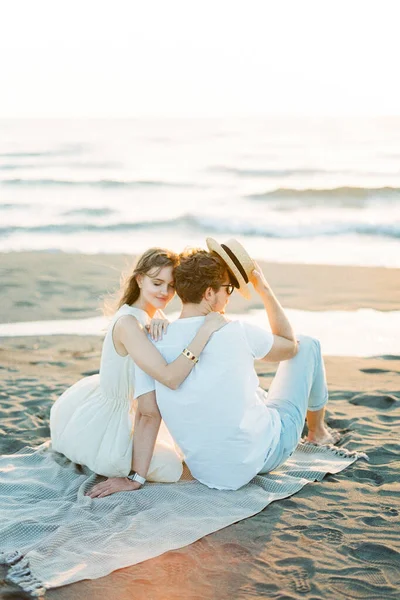 Woman hugging man shoulder while sitting on the beach. High quality photo