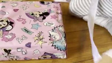 Little girl unties a ribbon on a gift with books. High quality 4k footage