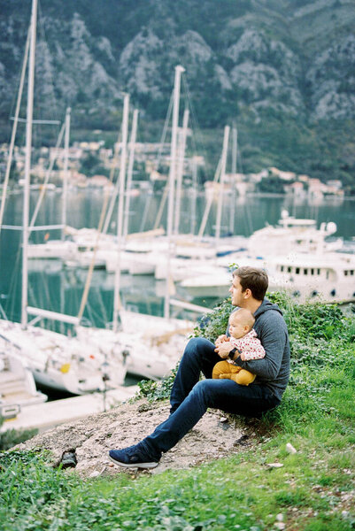 Dad Baby His Knee Sits Hill Looks Marina Moored Yachts — Stock Photo, Image