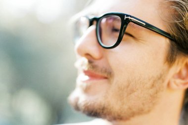 Young man with glasses squints at the sun. Profile. Portrait. High quality photo