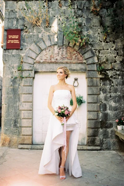 在一座古老的石头建筑旁边 站着穿着白色衣服的新娘 高质量的照片 — 图库照片