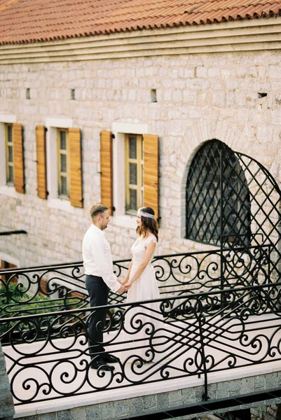 新娘和新郎手牵手站在旧石楼附近的桥上 高质量的照片 — 图库照片