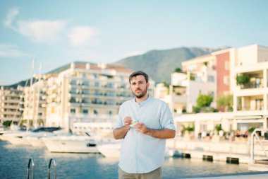 Elinde dondurma olan genç bir adam demirli yatlarla setin üzerinde duruyor. Yüksek kalite fotoğraf