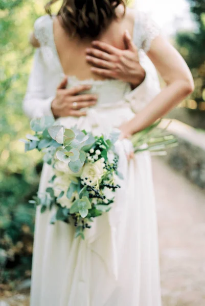 Bruidegom Handen Knuffelen Bruid Terug Met Een Boeket Bloemen Haar — Stockfoto