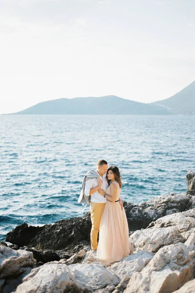 Vőlegény Kabátban Vállán Öleli Menyasszonyt Egy Sziklás Tengerparton Kiváló Minőségű — Stock Fotó