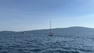 Yat, dağların arka planına karşı denizde yüzüyor. Yüksek kalite 4k görüntü
