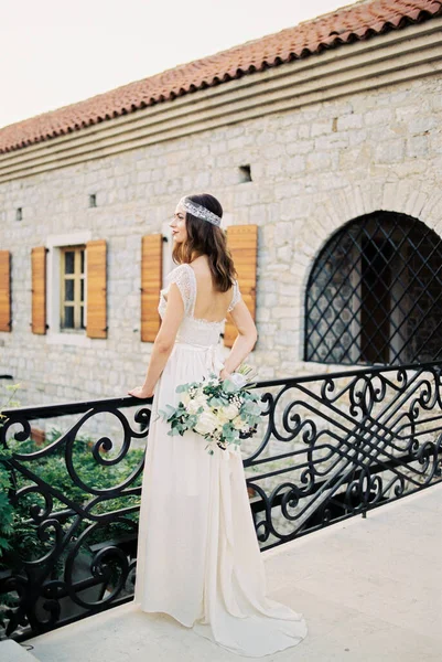 新娘带着一束鲜花站在一座旧石楼附近的一座桥上 高质量的照片 — 图库照片