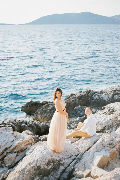 Pengantin Berdiri Setengah Berbalik Pantai Berbatu Dekat Pengantin Pria Duduk — Stok Foto