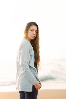 Süveterli bir kız deniz kıyısında yarı yolda duruyor. Yüksek kalite fotoğraf