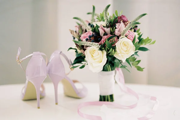 Sepatu Hak Tinggi Berdiri Atas Meja Putih Samping Karangan Bunga — Stok Foto